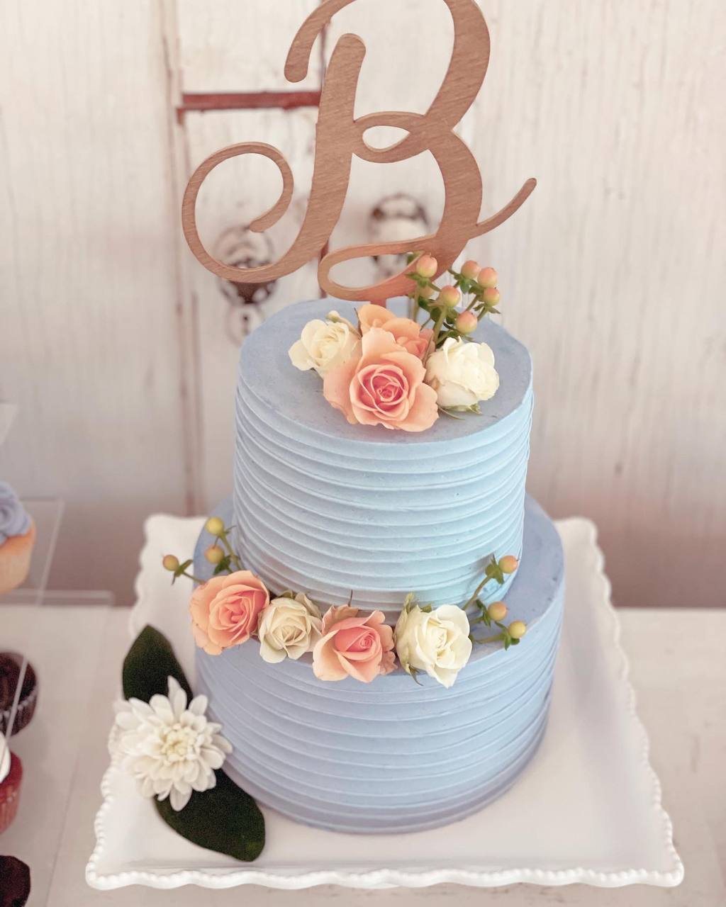 Two-tier blue wedding cake with fresh roses