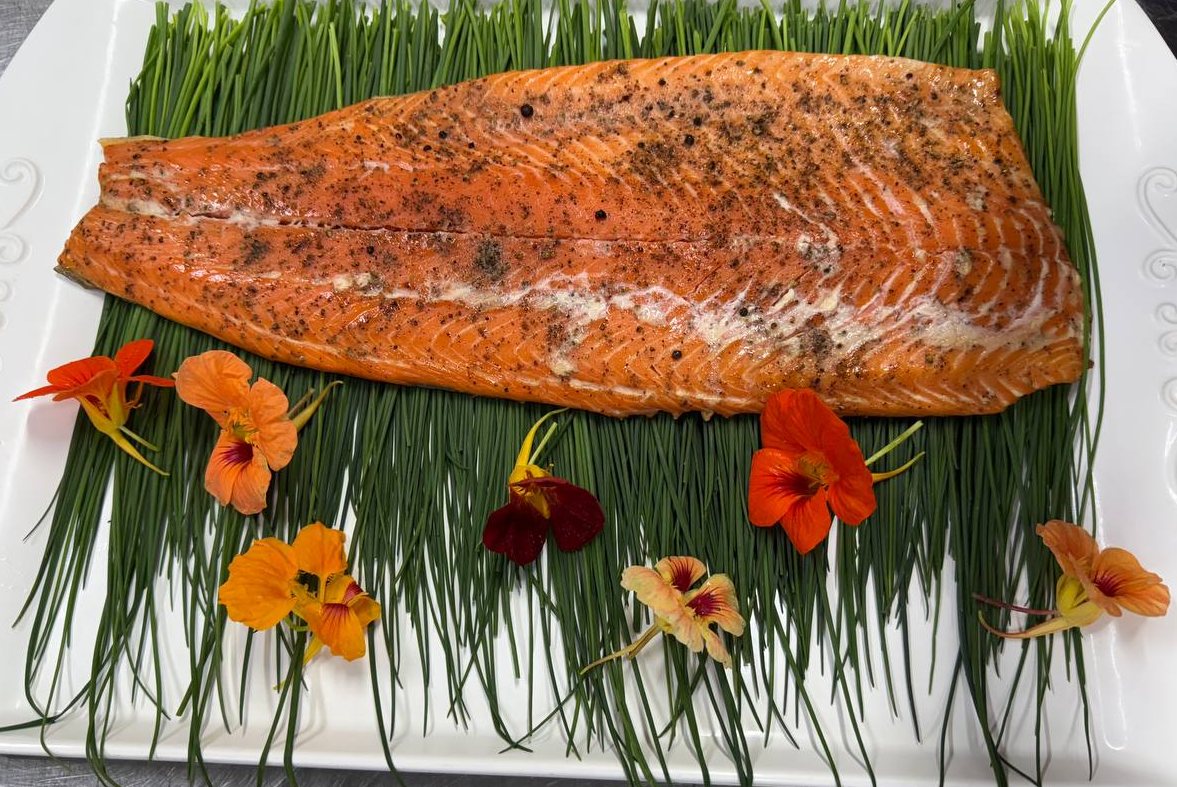 Cedar plank salmon on chive bed with edible flowers
